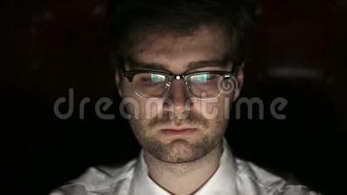 一个戴眼镜的年轻人晚上工作的肖像。 关门